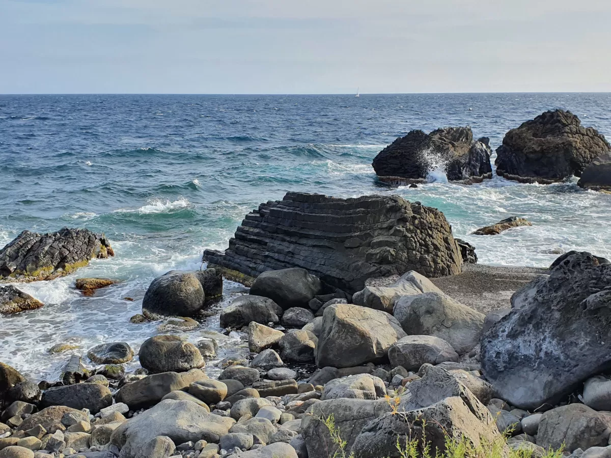 Spiaggia rocciosa con colonne di basalto lavico