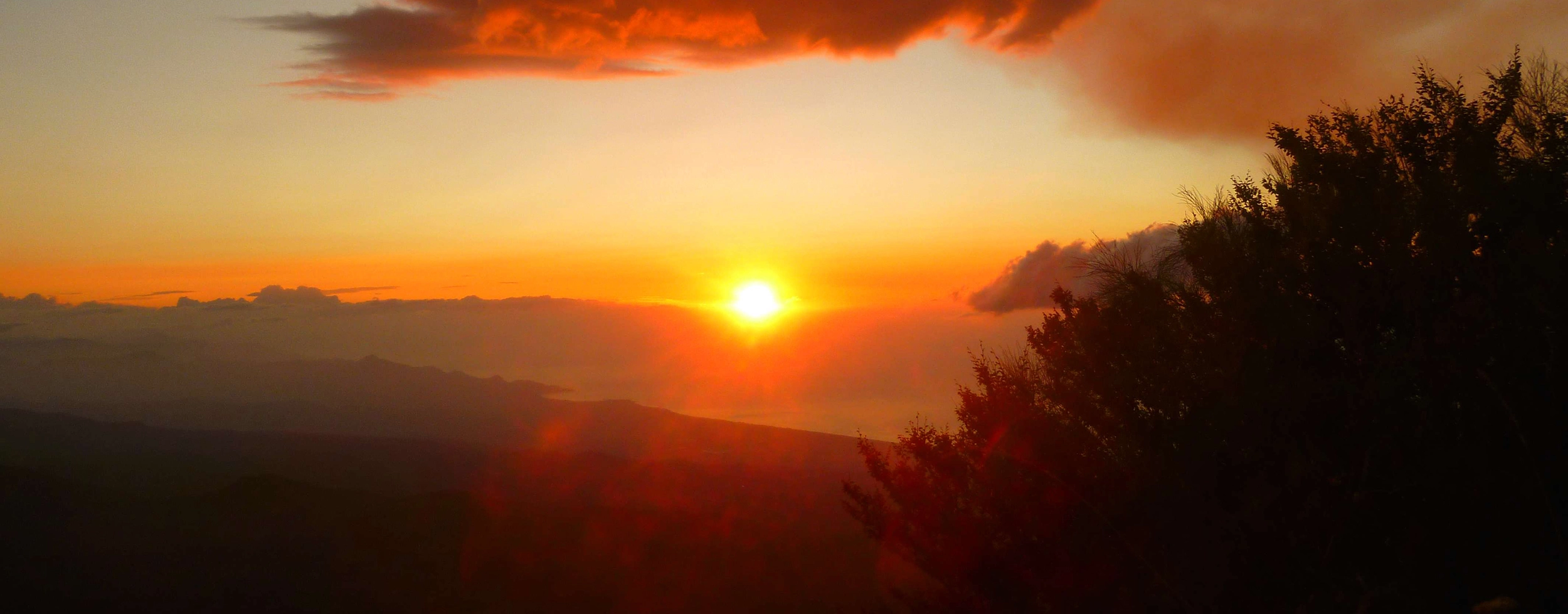 Black lava flows and extinct craters on Mount Etna illuminated by warm sunset light